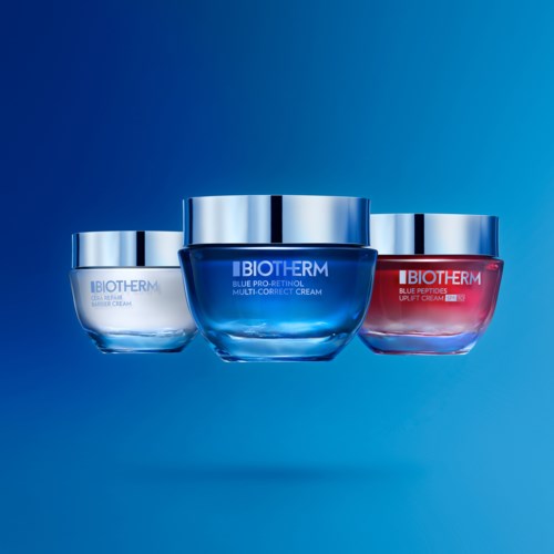 Kolme Biotherm-huoltotuotteiden purkkia sinisellä, punaisella ja läpikuultavalla pakkauksella sinisellä taustalla.