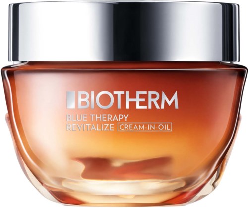 En burk med Biotherm Blue Therapy Revitalize cream-in-oil med ett silverlock och glas i bärnstensfärg.