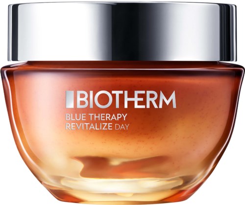 Et glass med Biotherm Blue Therapy Revitalize Day-ansiktskrem med sølvfarget lokk og oransjeaktig krem innvendig.