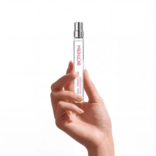 A hand holds a small clear bottle with a silver cap labeled BioTherm and vitamin C.