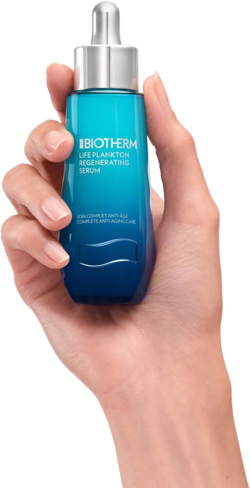 En hand håller en blå och silver serumflaska märkt "IBIOTHER...SERUM."
