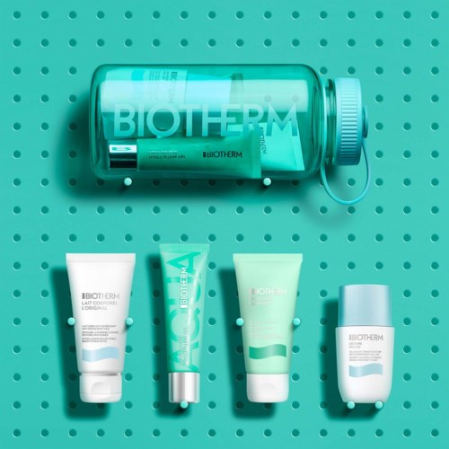 Ett transparent rör märkt Biotherm med fyra hudvårdsprodukter inuti, placerade på en turkos prickig bakgrund.