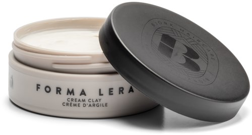 En krukke med krem med svart lokk merket 'Forma Lera' og 'Cream Clay', delvis åpen. Krukken inneholder hvit krem.