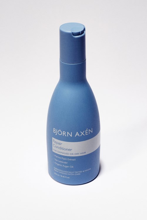 En blå flaska Björn Axén Repair Conditioner för torrt hår står upprätt på en vit bakgrund.
