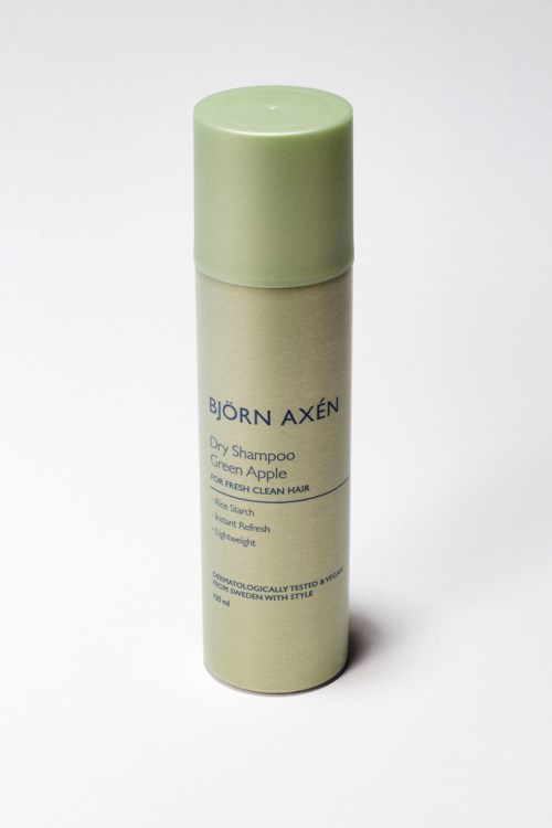 A beige spray bottle with a green cap labeled Björn Axén Dry Shampoo Green Apple.