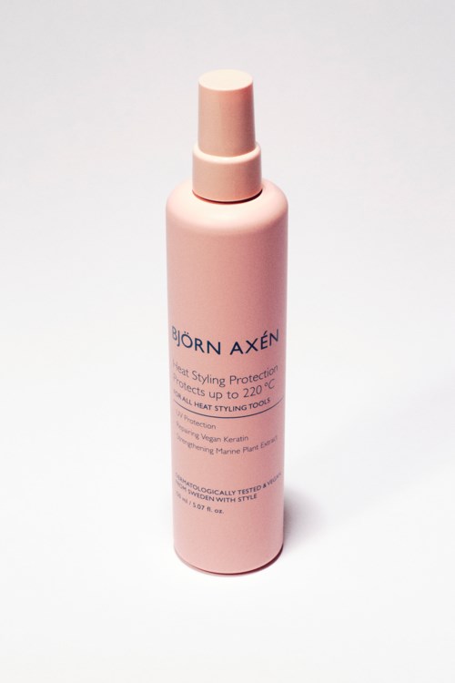 A pink spray bottle labeled Björn Axén, likely a hair product, with a pump top, standing on a white background.