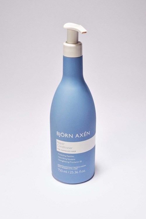 Een blauwe fles met een witte pomp, gemarkeerd "Björn Axén" en beschrijft haarverzorgingsproduct.