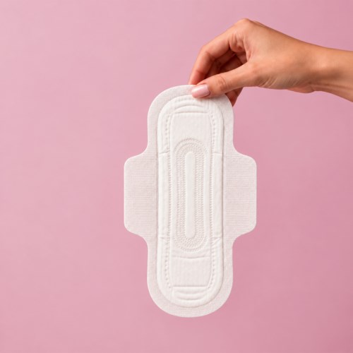 A hand holding a white sanitary pad against a pink background.
