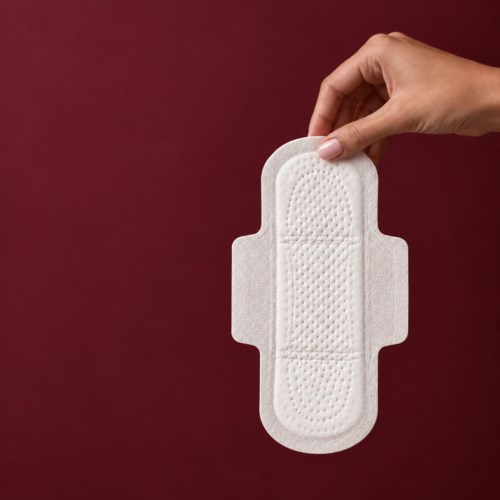 A hand holds a white adhesive bandage against a dark red background.