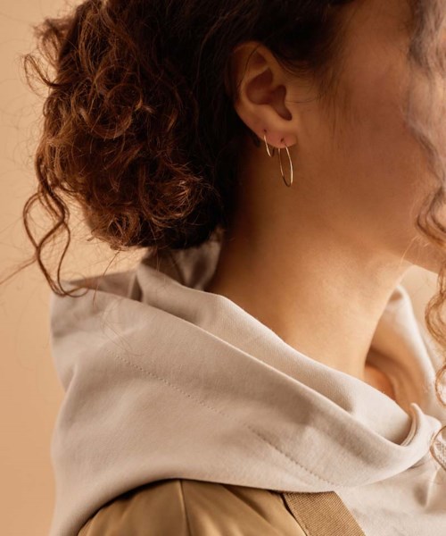 A woman with curly hair wearing earrings and a hoodie, facing to the side, close-up portrait.