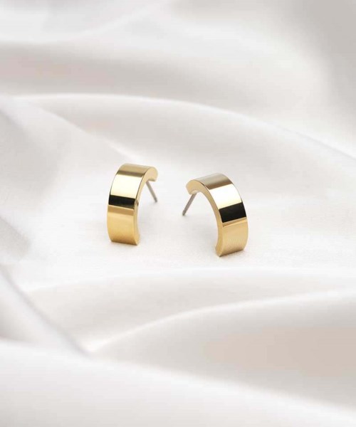 Gold half-circle earrings on white fabric background.