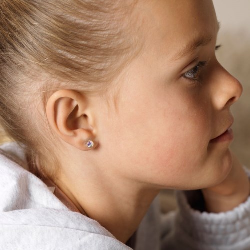 A young girl with blonde hair, wearing a white shirt and a small earring, in profile view.