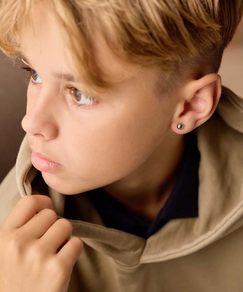 A young person with light hair, wearing a beige hoodie, looking thoughtfully to the side.