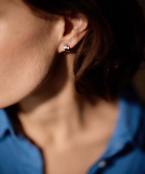 Close-up of a woman's face with a small earring showing on her ear, and her dark hair partly visible.