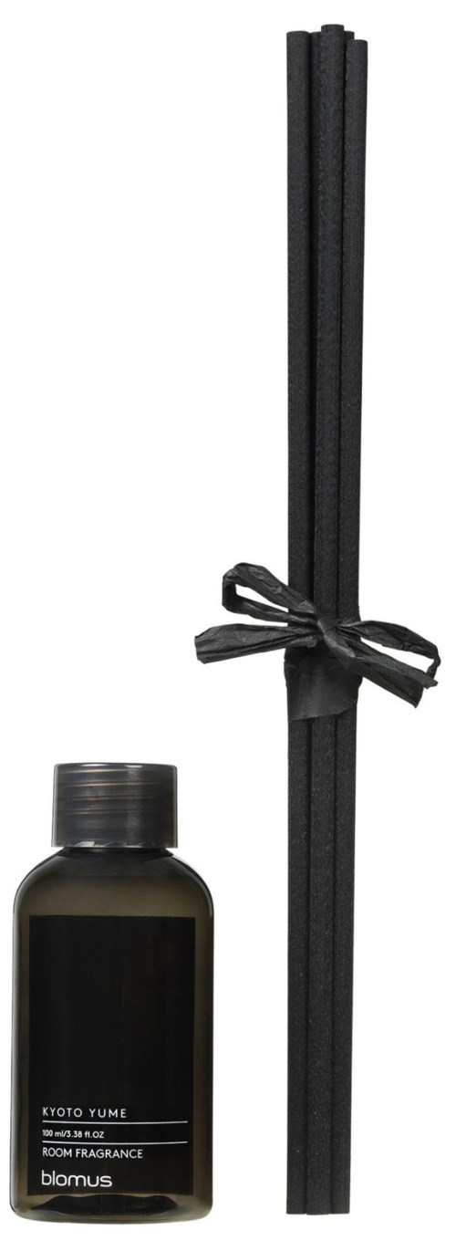 A black bottle of room fragrance and black sticks tied with a black ribbon. The bottle has a label and a screw cap.