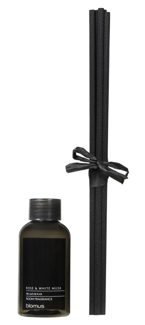 En flaske romduft og en bunt med svarte pinner bundet med bånd. Labelen leser "Rose & White Musk."