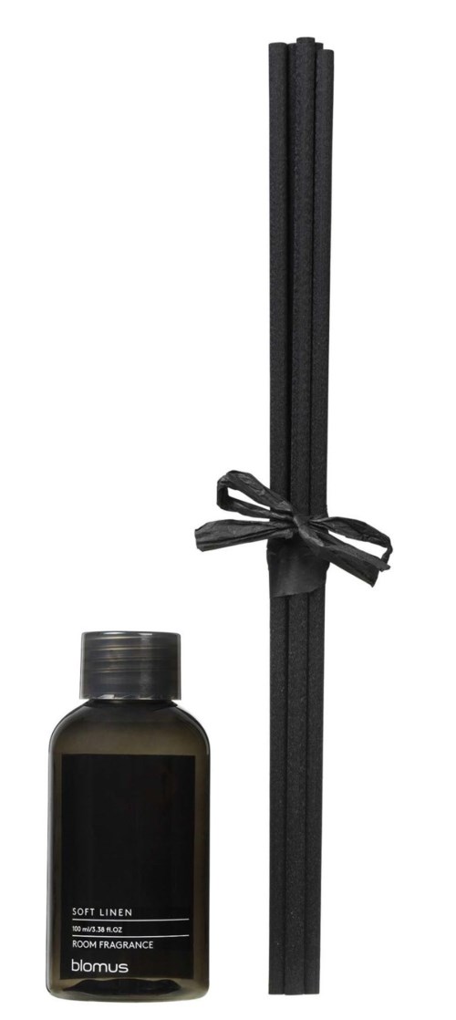 A black bottle of room fragrance sticks with a few matching sticks tied with a black ribbon.
