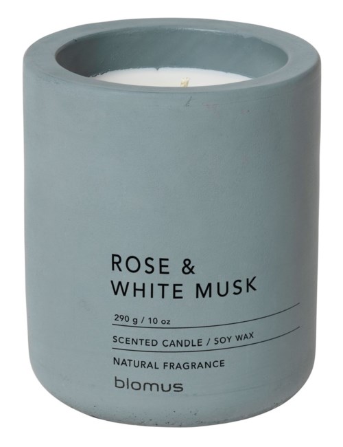 A light blue candle in a rounded container, labeled with scent and brand details.