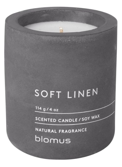A gray candle holder with a white candle inside, labeled 'Soft Linen' and scent details. Minimalistic design.