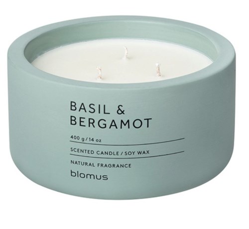 A light blue round candle labeled with scents basil and bergamot, made of soy wax, with three wicks inside.