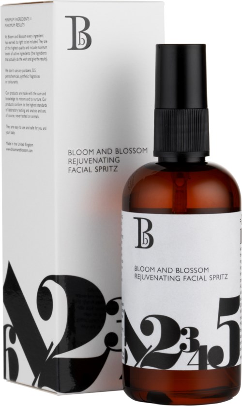 En brun flaska med svart spraylock, märkt 'Bloom and Blossom', bredvid en vit förpackning med samma etikett.