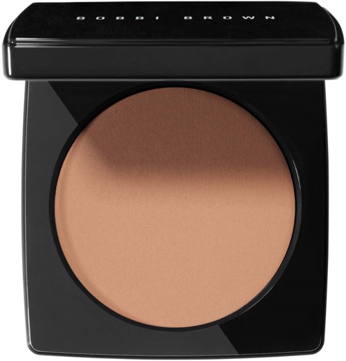 A compact beige powder in a black round case with a lid labeled "Bobby Brown".