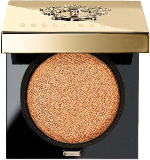 En rund, ferskenfarget blush med en teksturert overflate i en svart kompakt etui, med et skinnende gulllokk oppå.