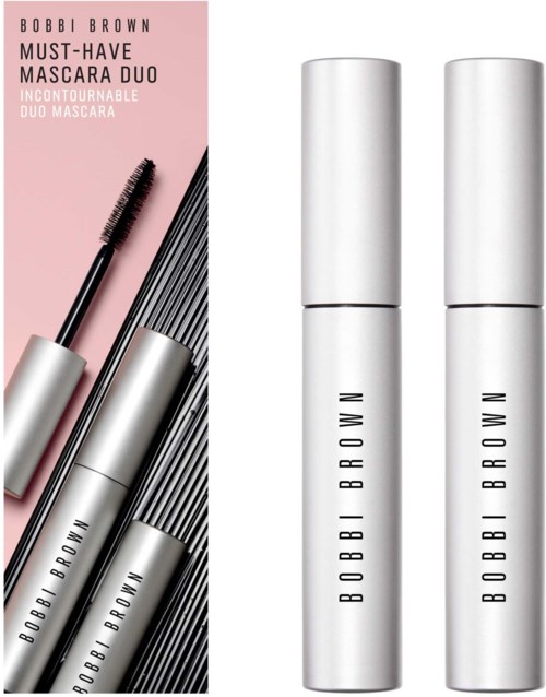 Zwei weiße runde Mascara-Hülsen und eine Mascara-Bürste sind zu sehen, mit rosa Hintergrund und schwarzen und weißen Linien.
