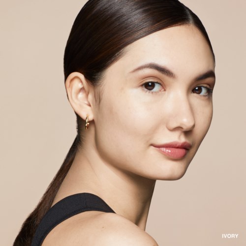 A young woman with long, dark hair, light skin, and a subtle smile, wearing a black sleeveless top.