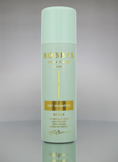 En lång, ljusgrön flaska märkt 'Bobby's Hair Care' med beskrivning för torrschampo och detox.