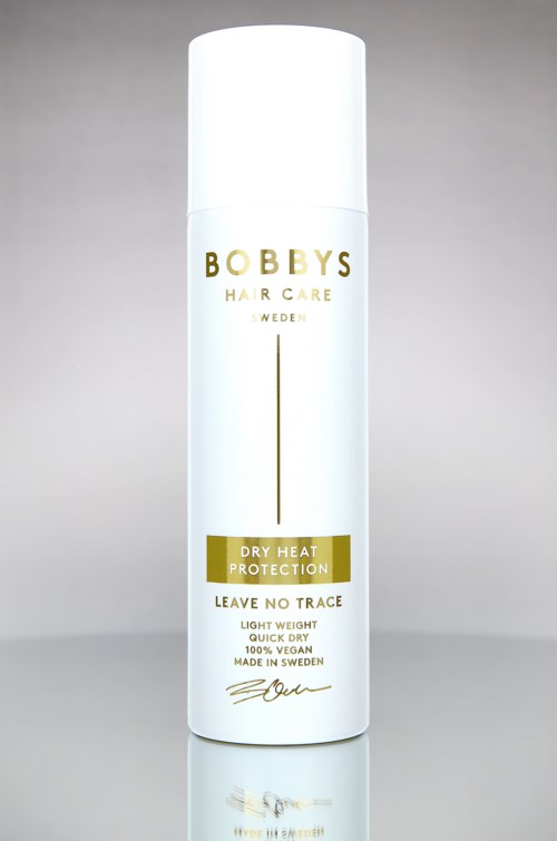 Een witte fles van Bobby's Hair Care met goud en zwart tekst, op een grijze achtergrond.