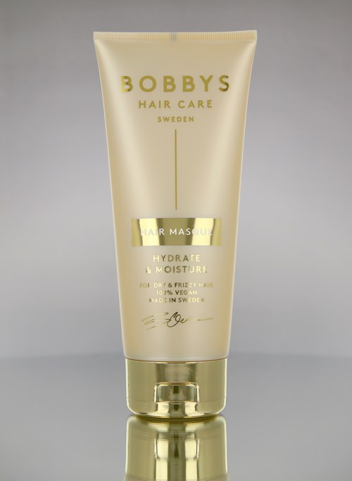 Een gele tube met Bobby's Hair Care, Zweden, voor haarmaskers, hydrateren en vocht, met gouden dop.