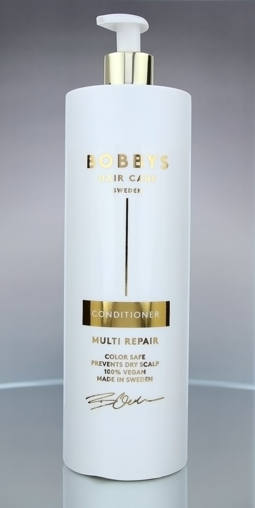 En lång vit flaska med guld och svart text, pumphuvud, märkt Bobbys hårvård balsam.