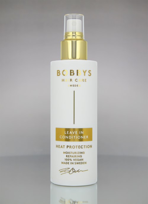 A white bottle with gold cap and yellow label, labeled 'Leave In Conditioner' for hair care.