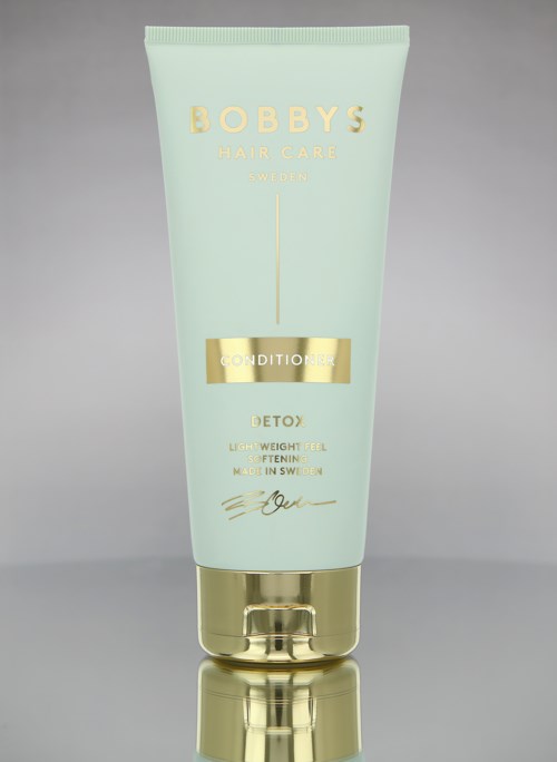 En lys grøn flaske med guld accenter mærket 'Bobby's Hair Care' og 'Conditioner' til hårpleje og detox.