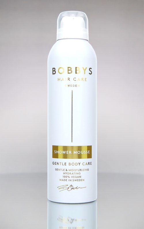 White bottle with gold and black text, called Bobby's Shower Mousse, for gentle body care.
