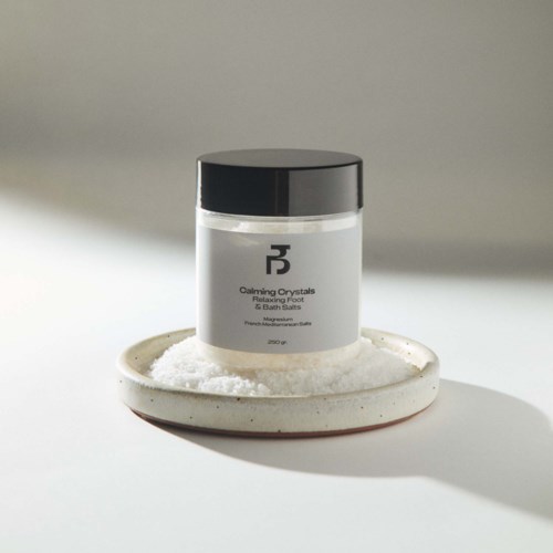 Lasis on merkintä 'Calming Crystals' ja se on valkoisen lautasen päällä suolan kanssa taustalla.