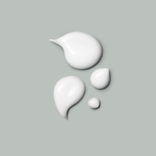 Several drops of white cream or lotion on a gray background.