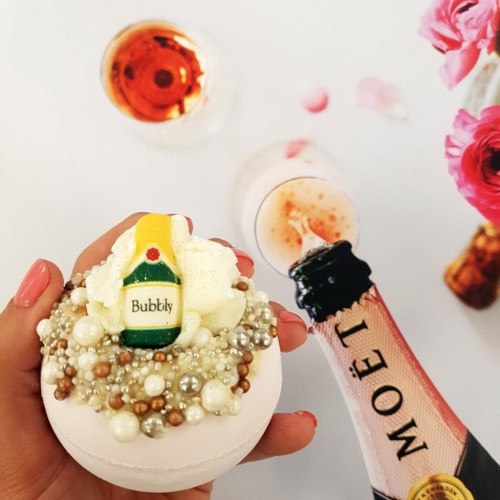 Dekorert cupcakes med perler, et lite gult innslag, omgitt av drikker og rosa blomster.