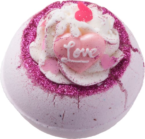 En badebombe med pink og hvid farve, pyntet med hjerter og ordet 'Love' på et rosa hjerte.
