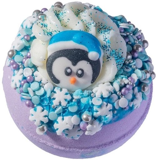 En rund kage pyntet med blå og hvid fondant, snefnug, en pingvinfigur og farverige små slik.