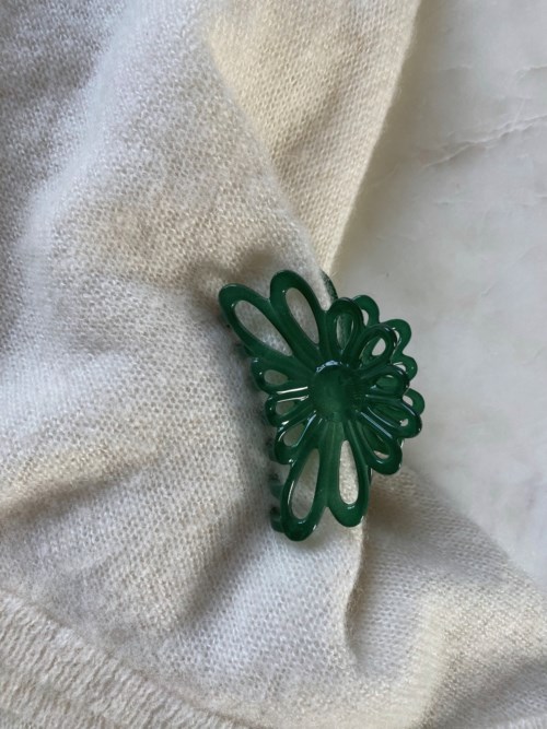Grøn plast sommerfuglformet broche fastgjort på stof.