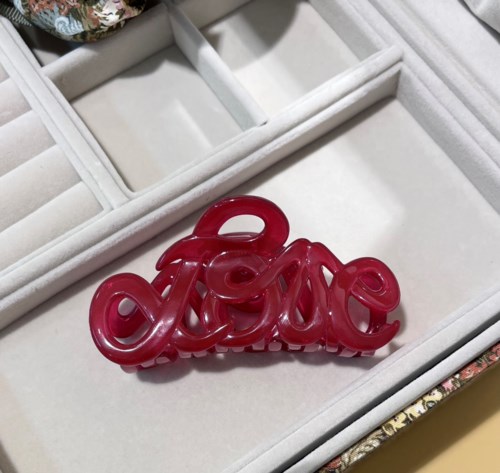 Ein rotes, glänzendes, dekoratives Wort 'love' in Kursiv, in einer weißen Schmuckschatulle.