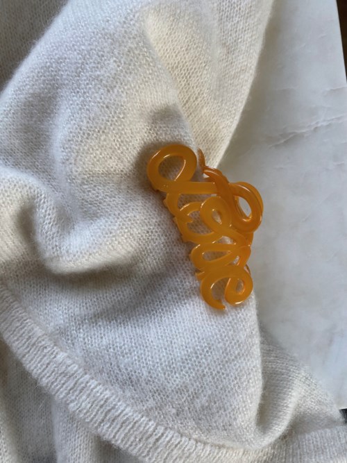 A yellow plastic pin with the word 'LOVE' on a white fabric background.