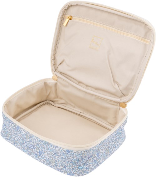 En liten reseväska med beige inuti och blå blommönstrad utsida, öppen visar ett fack och en dragkedjeficka.