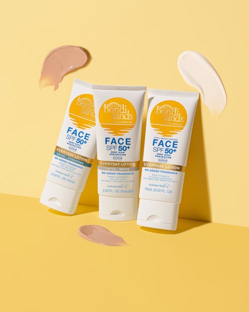 Tre tuber solcreme med SPF 50+ på gul baggrund, med cremer rundt.