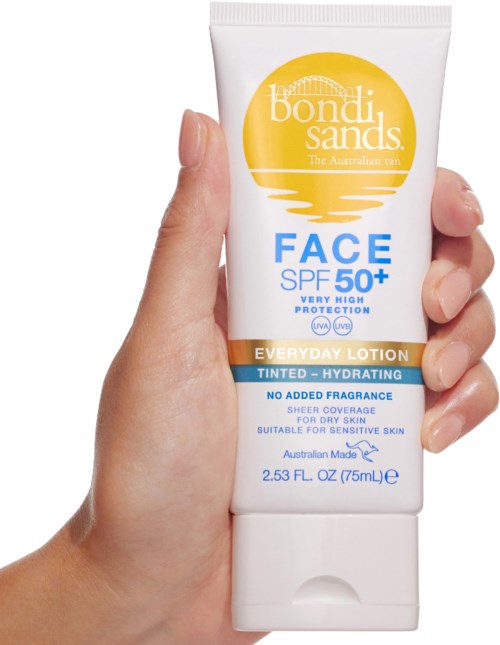 En hånd holder en hvit tube med Bondi Sands farget fuktighetsgivende ansiktslotion med SPF 50+, egnet for sensitiv hud.