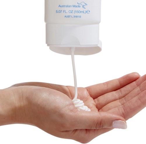 A hand catches white lotion from a pump bottle. The bottle indicates it is Australian-made body lotion, 150 ml.