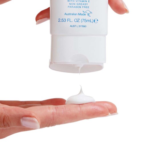 En persons hand håller en vit pumpflaska och pressar ut grädde i handflatan.