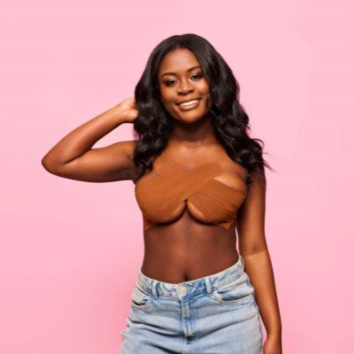 A woman with long black hair, wearing a brown top and light blue jeans, smiling against a pink background.